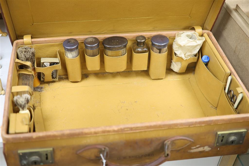 A gentlemans Edwardian leather cased travelling toilet set, including silver mounted glass toilet bottles